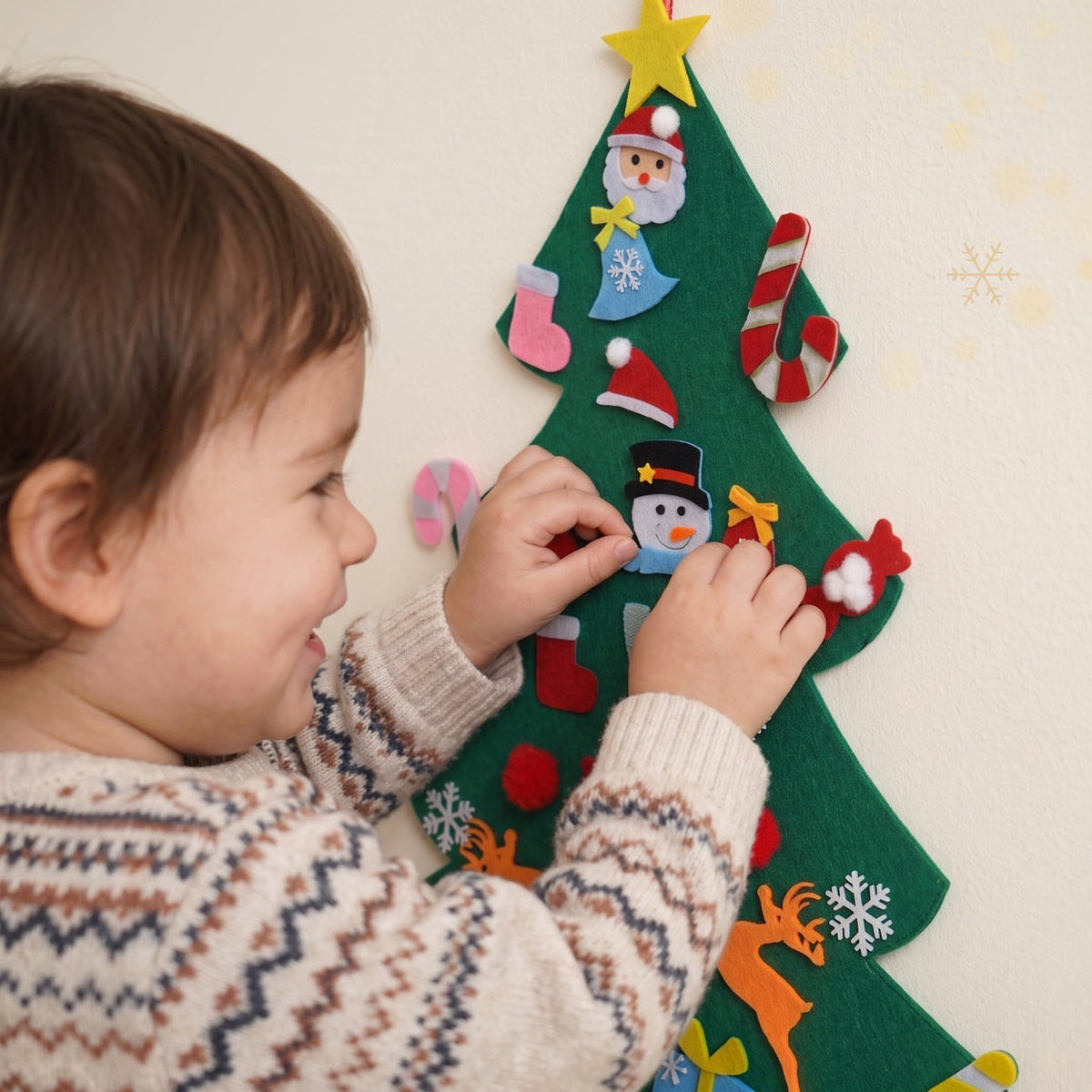 Bébé qui accroche un ornement sur le sapin en feutrine, en gros plan