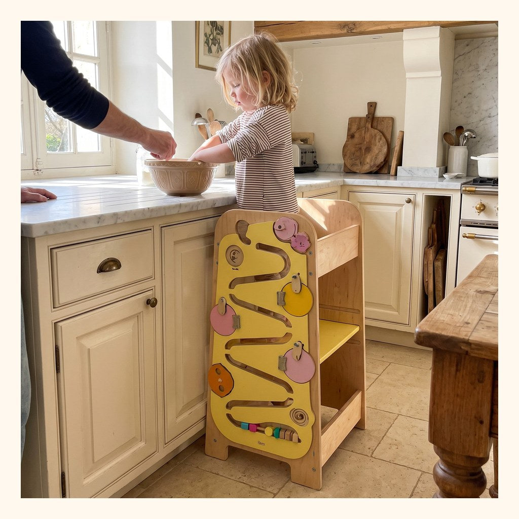 Enfant debout dans la tour d'apprentissage en bois, au plan de travail de la cuisine