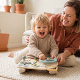 Enfant qui rit en tournant son volant Montessori en bois, sa maman à côté